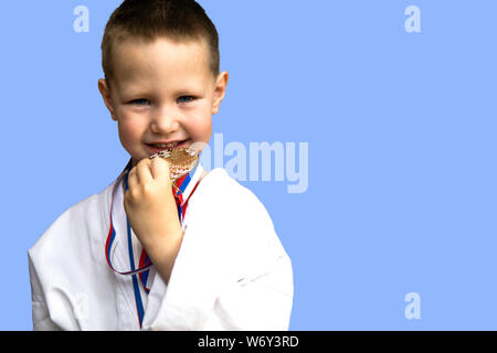 Sport di successo e vincere concetto - atleta sorridente champion bambino ragazzo mano che tiene il primo posto la vittoria della medaglia d'oro. Medaglia per il primo posto. Foto Stock