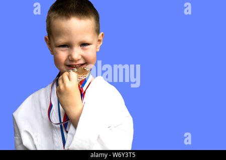 Sport di successo e vincere concetto - atleta sorridente champion bambino ragazzo mano che tiene il primo posto la vittoria della medaglia d'oro. Medaglia per il primo posto. Foto Stock