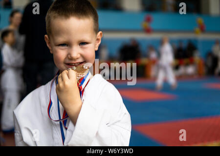 Sport di successo e vincere concetto - atleta sorridente champion bambino ragazzo mano che tiene il primo posto la vittoria della medaglia d'oro. Medaglia per il primo posto. Foto Stock