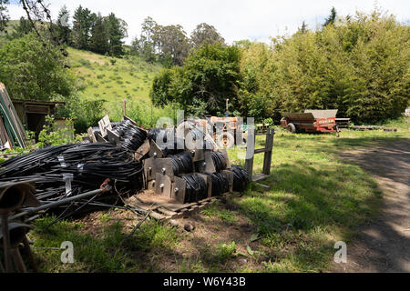 I vari tubi, trattori e macchine agricole sparse su erba presso l'azienda Foto Stock