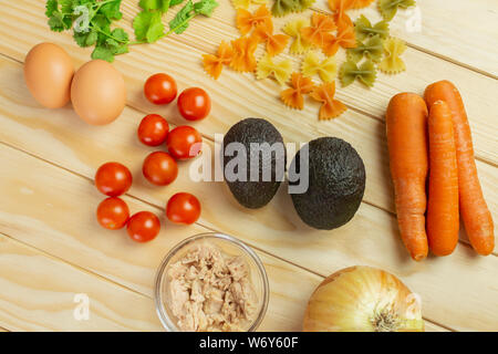 Cipolla, carota, tonno, avocado, prezzemolo, uova, pomodori e pasta, tutti freschi e pronti organico per cucinare Foto Stock