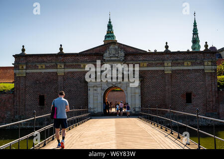 Kronborg, Danimarca -- Luglio 26, 2019. Un turista cammina su un ponte levatoio sopra un fossato sul suo modo di Kronborg Castle. Foto Stock