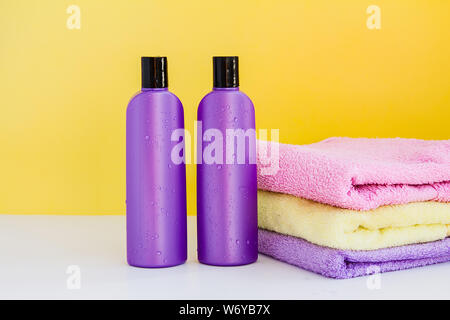 Due viola flaconi cosmetici e tre asciugamani da bagno per trattamenti Spa e il corpo e la cura dei capelli Foto Stock