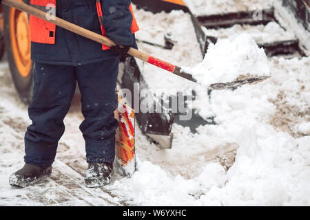 Rimozione della neve in città. Lavoratore aiuta la pala spartineve Foto Stock