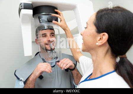 Bel uomo paziente in piedi nella macchina a raggi x. Radiografia panoramica di professional dental clinic. Foto Stock