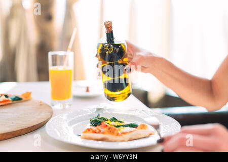 La ragazza versa olio una gustosa pizza. Foto Stock