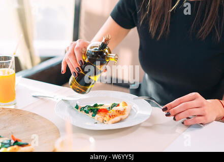 La ragazza versa olio una gustosa pizza. Foto Stock