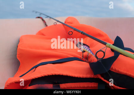 Canna da pesca per la pesca e il giubbotto di salvataggio è necessario quando la cattura di pesci predatori in mare Foto Stock