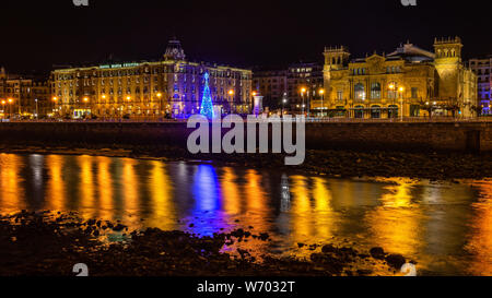 San Sebastian notte cityscape con due dei più eleganti edifici della città: Victoria Eugenia Teatro e Hotel Maria Cristina Foto Stock