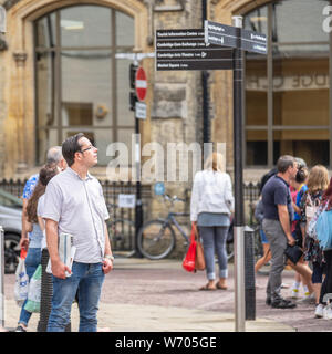 Cambridge, UK, 1 agosto 2019. Traveler direzioni di lettura ad attrazione turistica palina con indicazioni di direzione Foto Stock