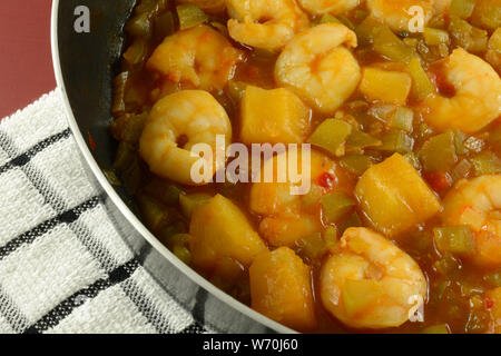 Hot dolce e piccante di gamberi con peperoni e ananas in antiaderente padella su asciugamano sul tavolo Foto Stock