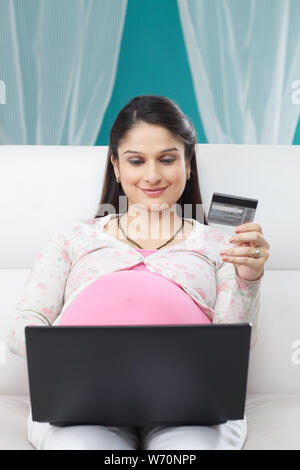 Donna incinta che fa shopping online con una carta di credito Foto Stock