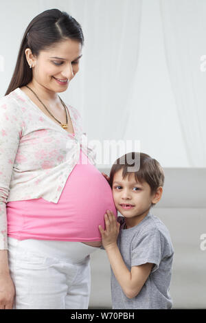 Ascolto bambino nel ventre di sua madre in stato di gravidanza Foto Stock