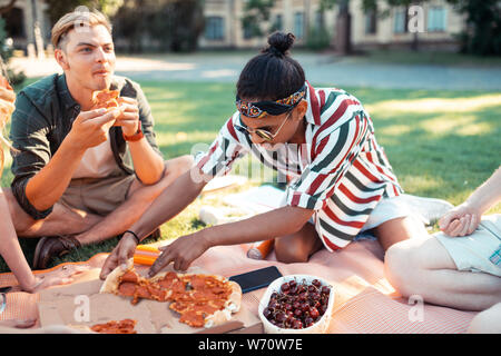 Ragazzo avente un picnic con i suoi amici universitari. Foto Stock