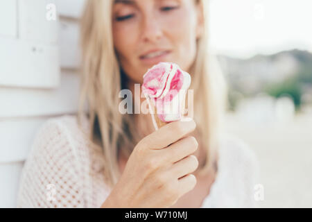 Donna 30 tiene nelle sue mani la fusione gelato alla fragola nel cono nelle sue mani Foto Stock