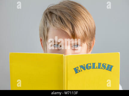 Bello preteen schoolboy holding giallo libro inglese, istruzione moderna, lingue straniere Foto Stock