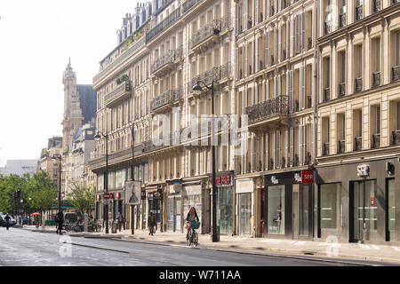 Paris street donna ciclismo - mattina street scene su Rue de Rivoli nel quartiere Marais di Parigi, in Francia, in Europa. Foto Stock