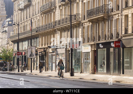 Paris street donna ciclismo - mattina street scene su Rue de Rivoli nel quartiere Marais di Parigi, in Francia, in Europa. Foto Stock