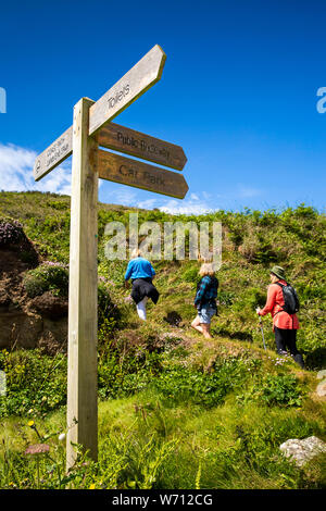 Regno Unito, Inghilterra, Cornwall, Porthgwarra, tre donne camminando sul percorso della costa intorno a testa Gwennap al cartello in legno Foto Stock