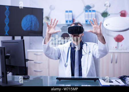 Maschio caucasico medico indossando occhiali per realtà virtuale test risultati del paziente. Tecnologia innovativi per i medici. Foto Stock