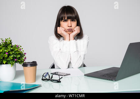 Annoiato donna nel lavoro di ufficio con un computer portatile e a fissare lo schermo del computer Foto Stock