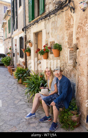 Coppia giovane seduto sulla panca sulla romantica strada del mediterraneo Foto Stock