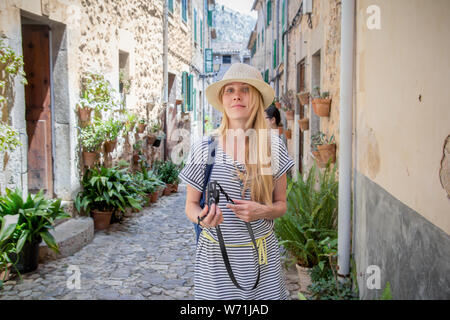 Giovane donna turistico con telecamera a piedi giù per la strada incantevole in città del Mediterraneo in estate Foto Stock