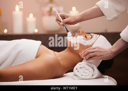 Vista laterale ritratto della splendida razza mista donna godendo facial therapy in spa di lusso, spazio di copia Foto Stock