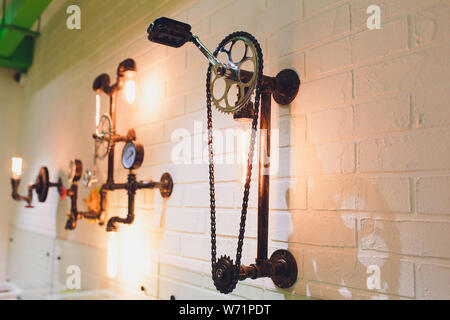 Steampunk stile architettonico elemento di design di interni. Le lampadine fisso sul ferro da stiro industriale ruote dentate ingranaggio pignone illuminato illuminazione attrezzatura Foto Stock