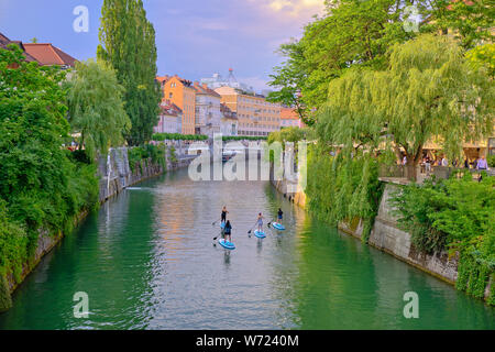 Equitazione turistica stand up paddle board giù il fiume attraverso il centro storico della città di Lubiana, Slovenia, Giugno 2019 Foto Stock