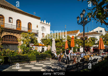 Novembre 21, 2017 - MARBELLA, Spagna. Le persone aventi il pranzo al di fuori in una piazza pubblica in una giornata di sole. Tradizionali edifici di colore bianco. Foto Stock