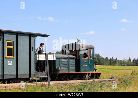 Spostare21 locomotiva diesel 67 passa bandiera rurale stop sul museo Jokioinen ferrovia, ispettore del biglietto in attesa. Palomaki, Finlandia. Luglio 28, 2019. Foto Stock