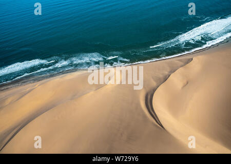 Vista aerea della Skeleton Coast dune di sabbia incontro onde dell oceano Atlanic. Skeleton Coast, Namibia. Foto Stock