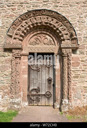 Porta e arco con sculture ornate sopra porta sud. Compreso l'angelo in centro. Chiesa di Santa Maria e San Davide, Kilpeck, Herefordshire Foto Stock