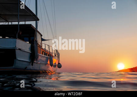 Un drammatico colpo di un caicco con il sole di setting come sfondo Foto Stock