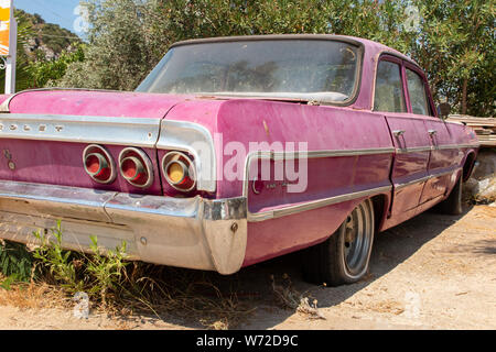 Una bella ma abbandonata dagli anni sessanta Chevy Impala con erbacce crescere intorno ad esso Foto Stock