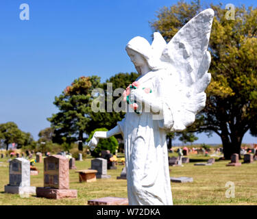 Un bianco grande statua angelo veglia su di tombe nel cimitero di Carney fuori Carney Oklahoma. Foto Stock