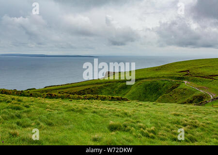 Seascape e un sentiero rurale tra la campagna irlandese del percorso costiero a piedi da Doolin per le scogliere di Moher, Wild Atlantic modo, giornata di primavera Foto Stock