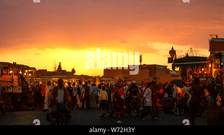 Folla di visitatori su Jem El Fna sotto i raggi del sole di setting Foto Stock