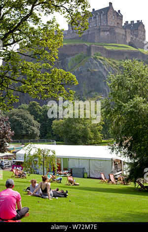 I giardini di Princes Street West, Edimburgo, Scozia, Regno Unito. 4 agosto 2019. Alcune persone hanno deciso di perdere le strade affollate del Fringe Festival e regolate per la tranquillità dei giardini in un caldo pomeriggio con la quinta scenografica del Ross Fontana e il castello. Foto Stock