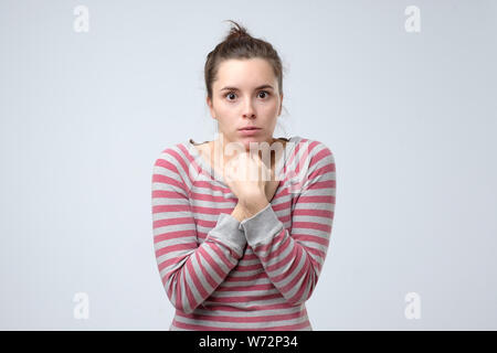 Ragazza disperata trema e sente freddo, huggs se stessa a warm up. Spaventata donna pazzesca nota qualcosa terrificante Foto Stock