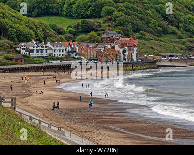 Sandsend sulla North Yorkshire Costa con i visitatori per godersi la spiaggia con onde che si infrangono lungo di essa Foto Stock