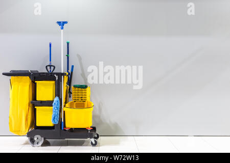Giallo mop benna e set di attrezzature per la pulizia e il segno di uomini wc sulla parete in aeroporto Foto Stock