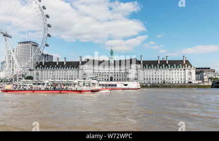London / UK, 15 Luglio 2019 - County Hall e per il London Eye, visto attraverso il fiume Tamigi Foto Stock