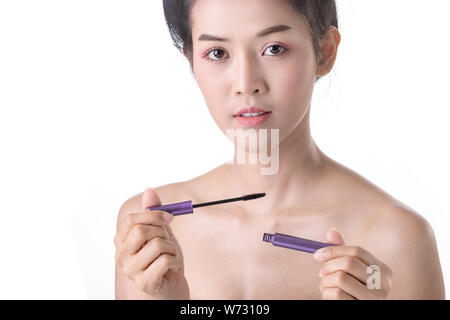 Vista ritagliata della donna asiatica con il trucco tenendo l'applicatore  mascara isolato su marrone, immagine stock Foto stock - Alamy