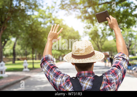 Asian per turisti in cerca e ricerca del proprietario del portafoglio nero che ha trovato in attrazione turistica. Perdere il concetto di portafoglio Foto Stock