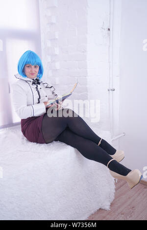 Piuttosto plus ragazza taglia in parrucca blu hanno molti sogni con il suo diario da sola seduta sul davanzale bianco Foto Stock