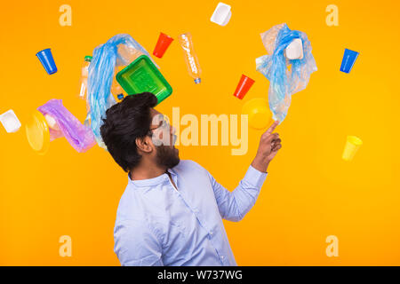 Inquinamento Ambientale, plastica problema di riciclaggio e smaltimento dei rifiuti Nozione - sorpreso uomo indiano punto sul cestino su sfondo giallo Foto Stock