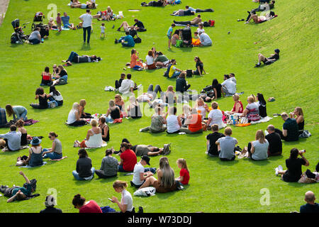 Gente seduta sul prato di Princes Street Gardens nel caldo clima estivo di Edimburgo, Scozia UK Foto Stock