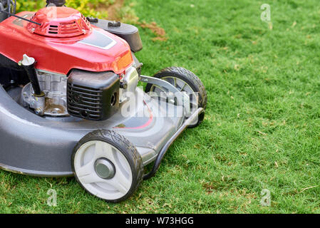 Lawn mover su erba verde in giardino vicino fino Foto Stock